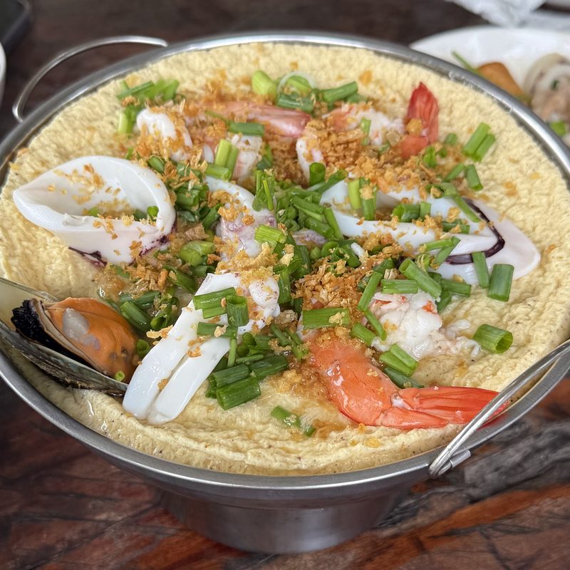 หม้อไข่ตุ๋นหน้าอาหารทะเล มีหมึก กุ้ง หอยแมลงภู่ ต้นหอม และกระเทียมเจียว