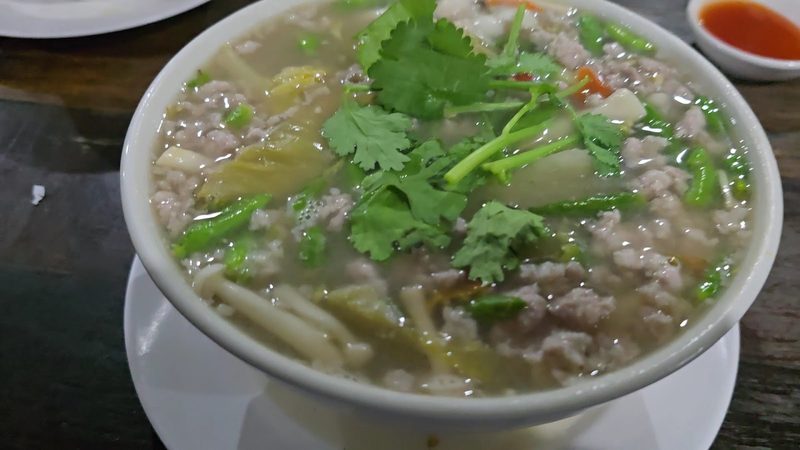 ต้มน้ำใสใส่หมูสับ ผักดอง และผักชีในชามขาว